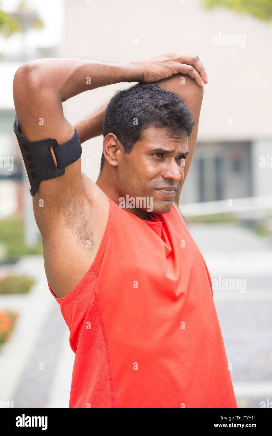 Atleta uomo indiano stretching all aperto in città urbana. Maschio di concetto di fitness. Foto Stock