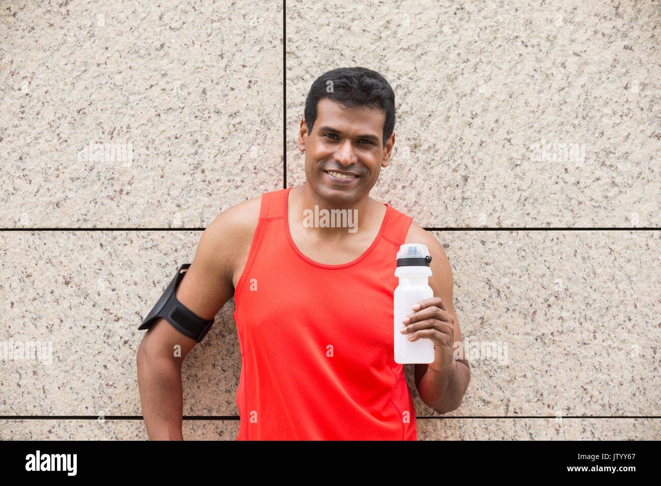 Ritratto di atletica uomo indiano riposando dopo aver percorso urbano attraverso le strade delle città. Maschio asiatici runner prendendo pausa rilassante permanente. Foto Stock