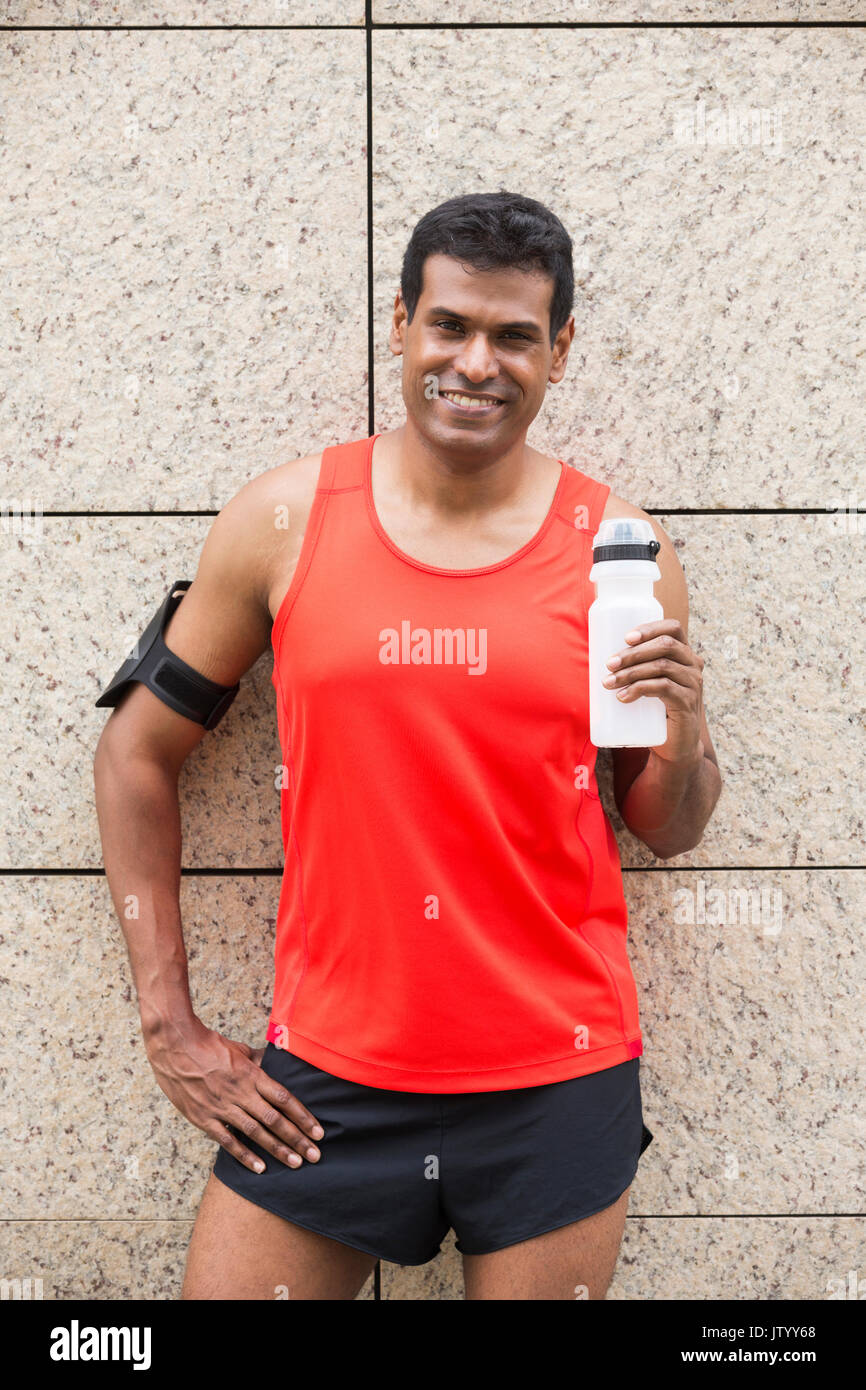 Ritratto di atletica uomo indiano riposando dopo aver percorso urbano attraverso le strade delle città. Maschio asiatici runner prendendo pausa rilassante permanente. Foto Stock