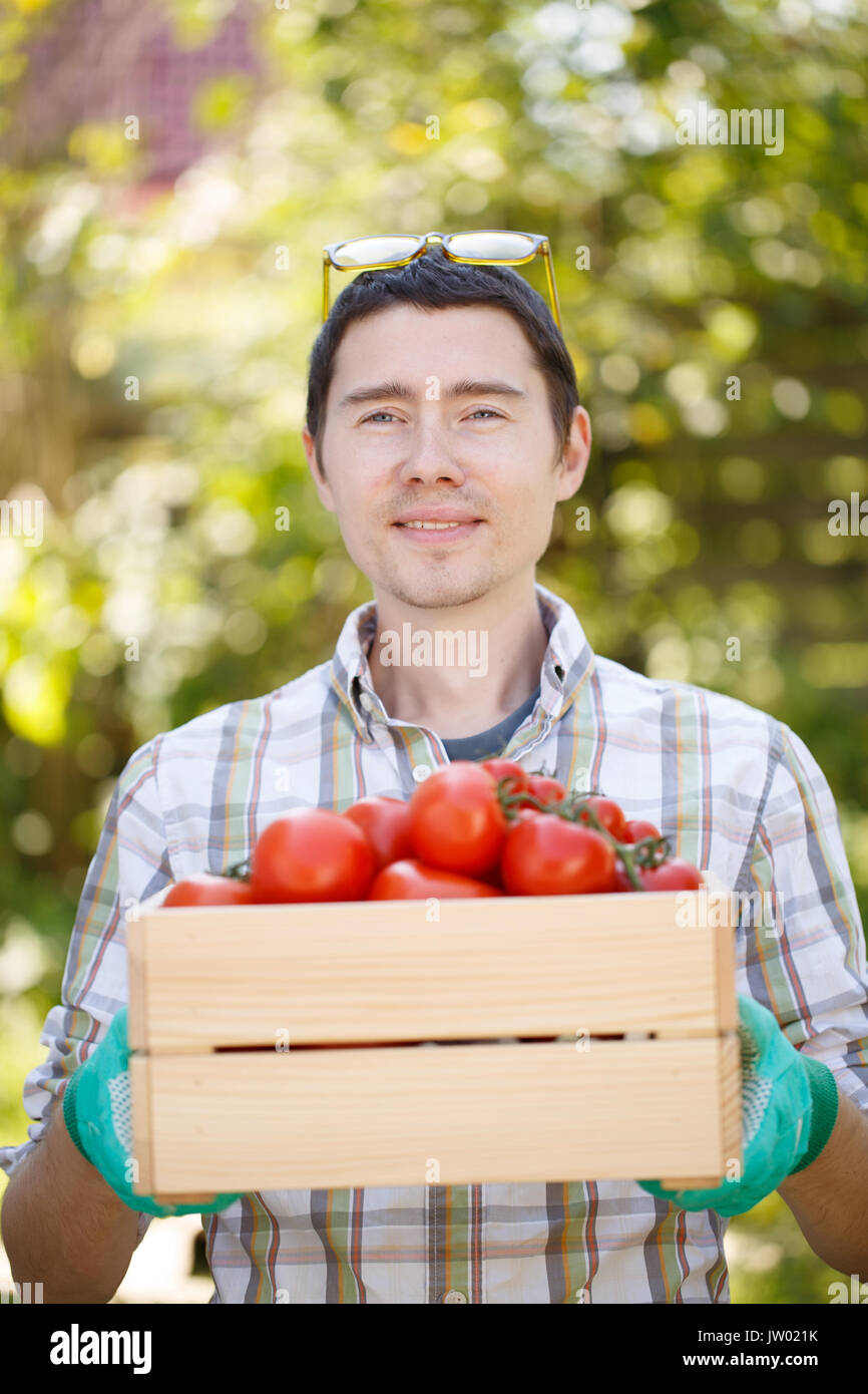 Ritratto di uomo in bicchieri con scatola di pomodoro su sfondo sfocato durante il giorno in estate Foto Stock