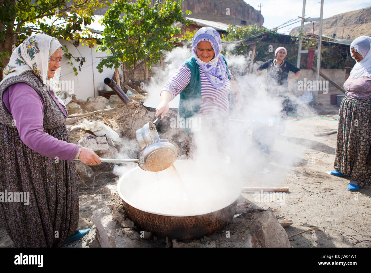 Le donne turche stanno rendendo Pekmez sulle strade della Cappadocia. Pekmez è una melassa-come sciroppo ottenuto dopo la condensazione succhi di frutta deve soprattutto uva mediante ebollizione. È usato come uno sciroppo o miscelato con tahini per colazione. Foto Stock