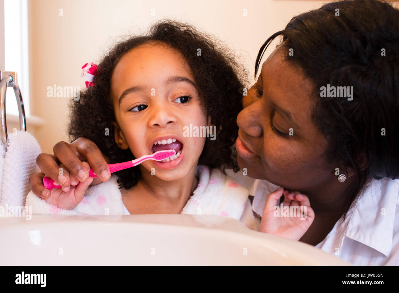 Una madre aiuta il suo giovane figlia lavarsi i denti. Foto Stock