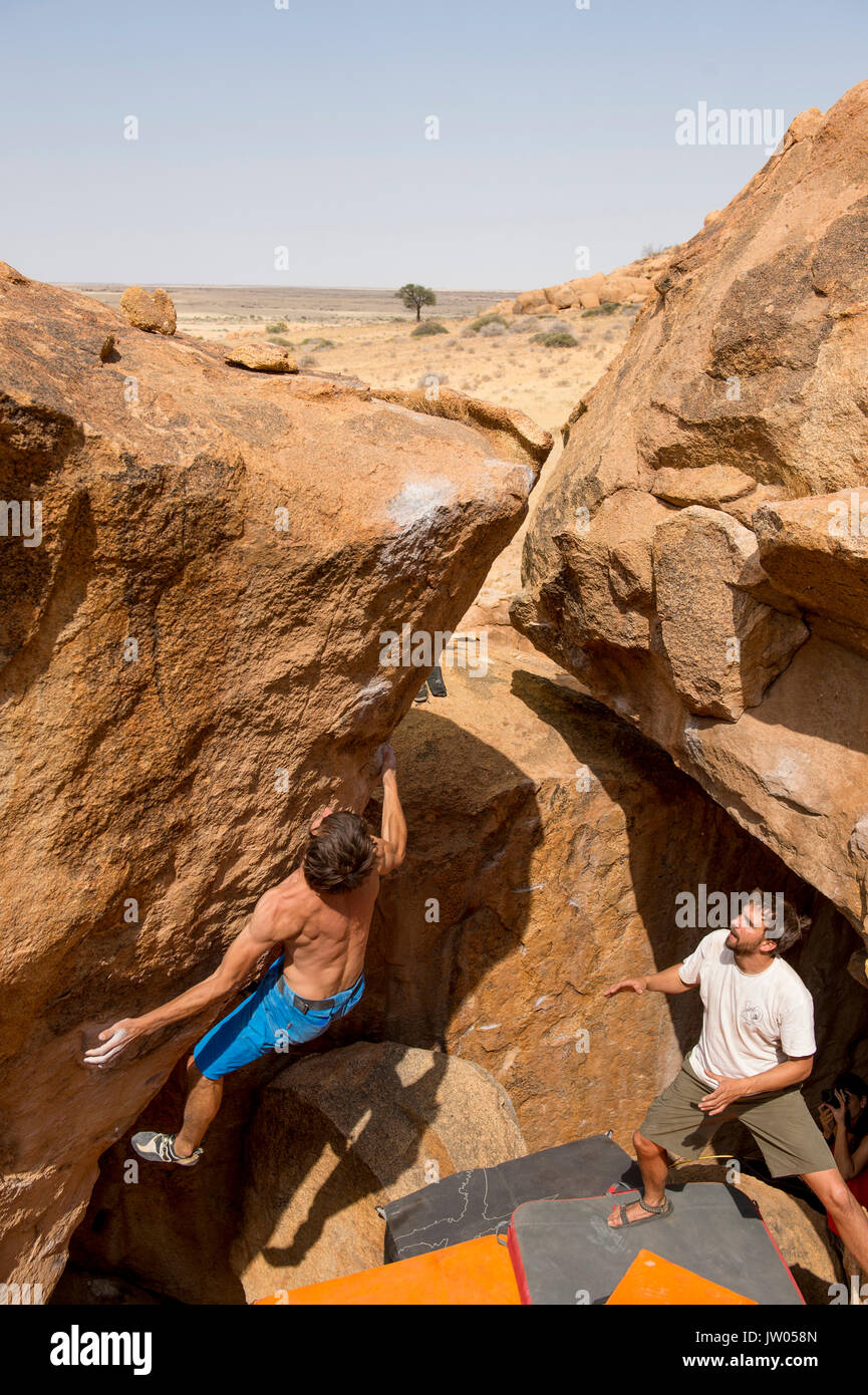 Un uomo bouldering e altri a guardare, Spitzkoppe, Regione di Erongo, Namibia Foto Stock