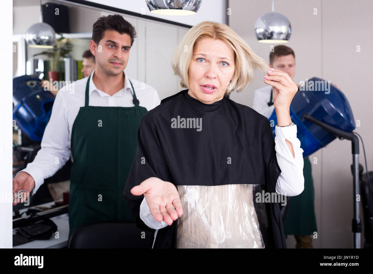 Frustrati pensionato femmina avente lotta con parrucchiere in salone. Focus sulla donna Foto Stock
