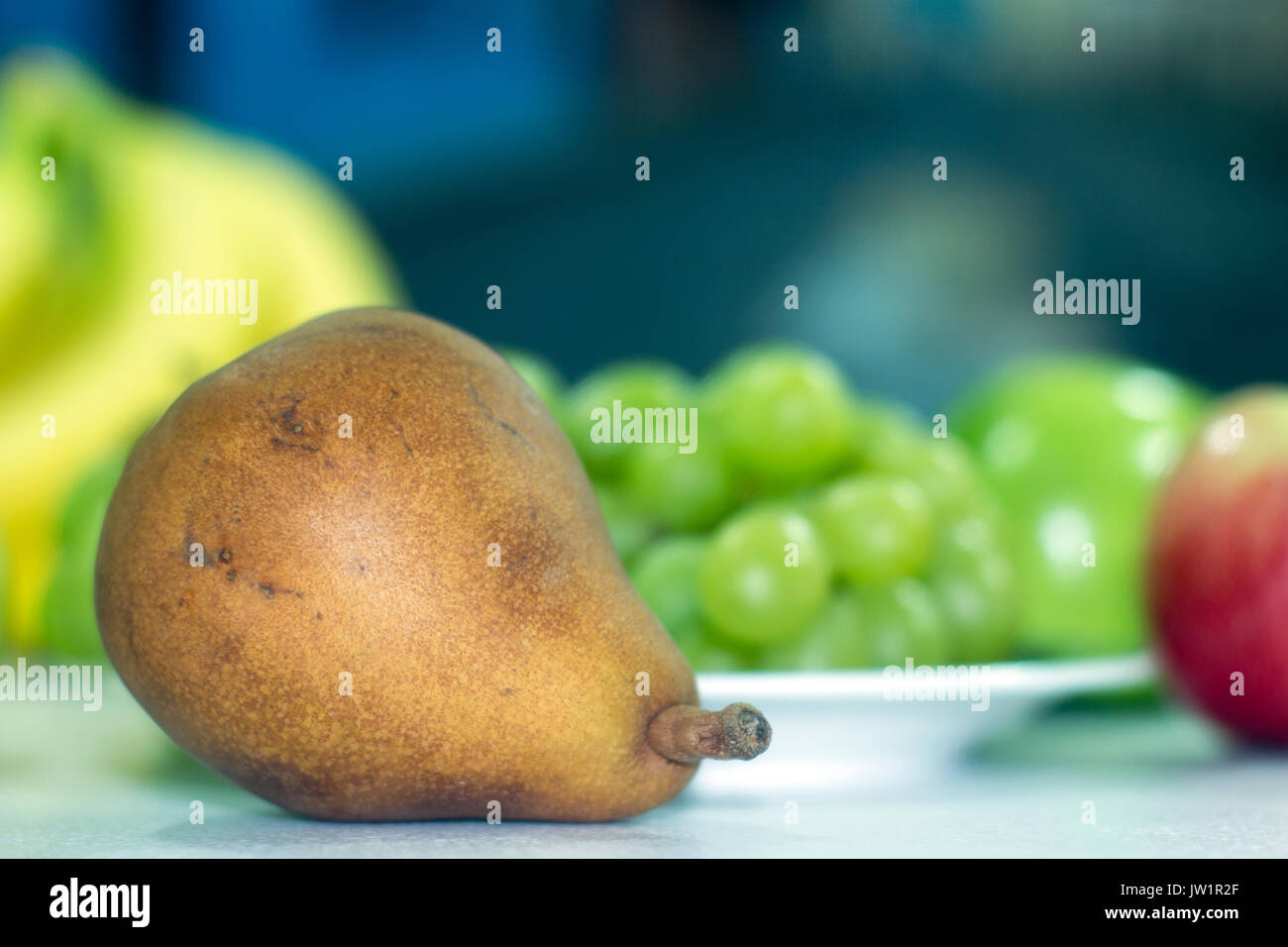 Pera en meza con otras frutas desenfocadas, alimento saludable y naturale vitaminas biella, baja en calorías, apetecible y jugosa, de color café Foto Stock