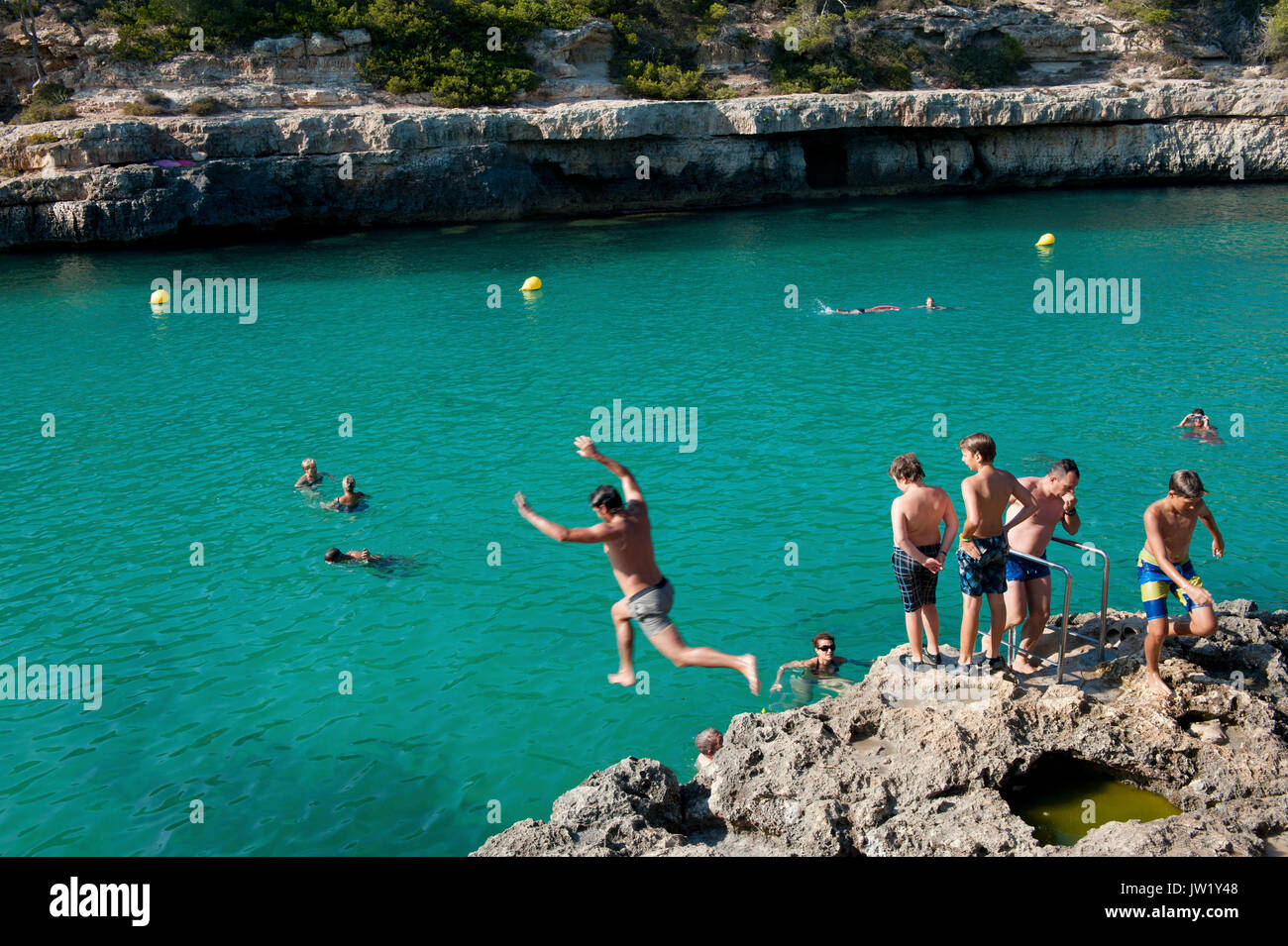 Nuotatori e lucertole da mare godendo una giornata di sole, Cala Llombards, Maiorca, SPAGNA Foto Stock