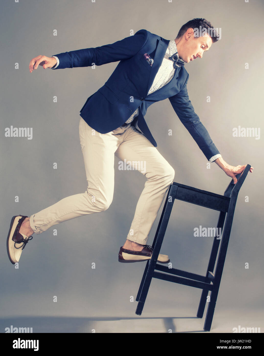 Giovane imprenditore handsoman ingannare geografica con sedia, moderno mem Foto Stock