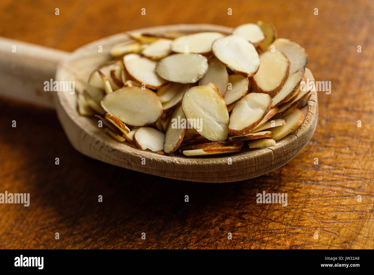 Cucchiaio di legno pieno di mandorle a pezzi sul tavolo Foto Stock