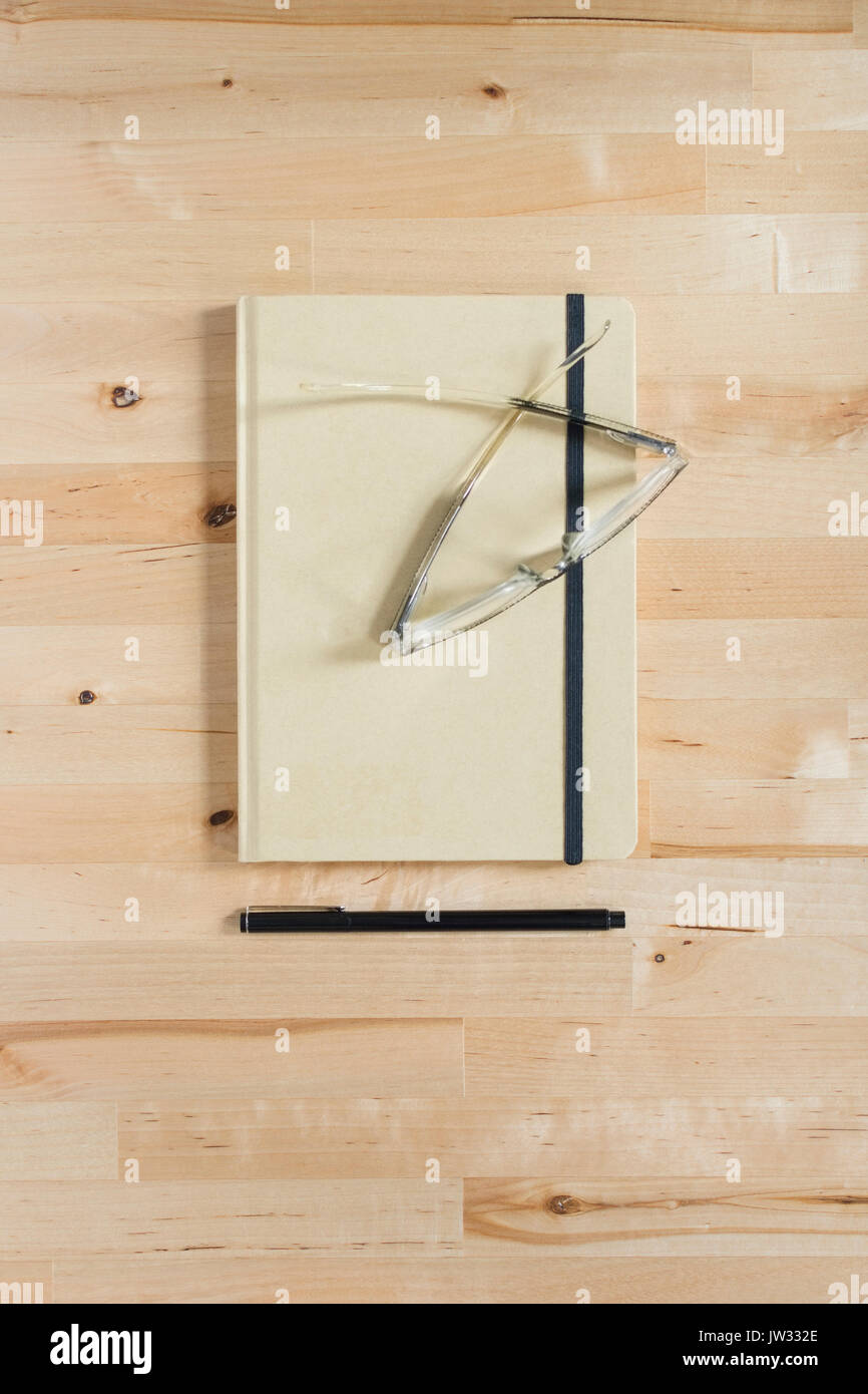 Diario, occhiali e penna sulla scrivania in legno Foto Stock