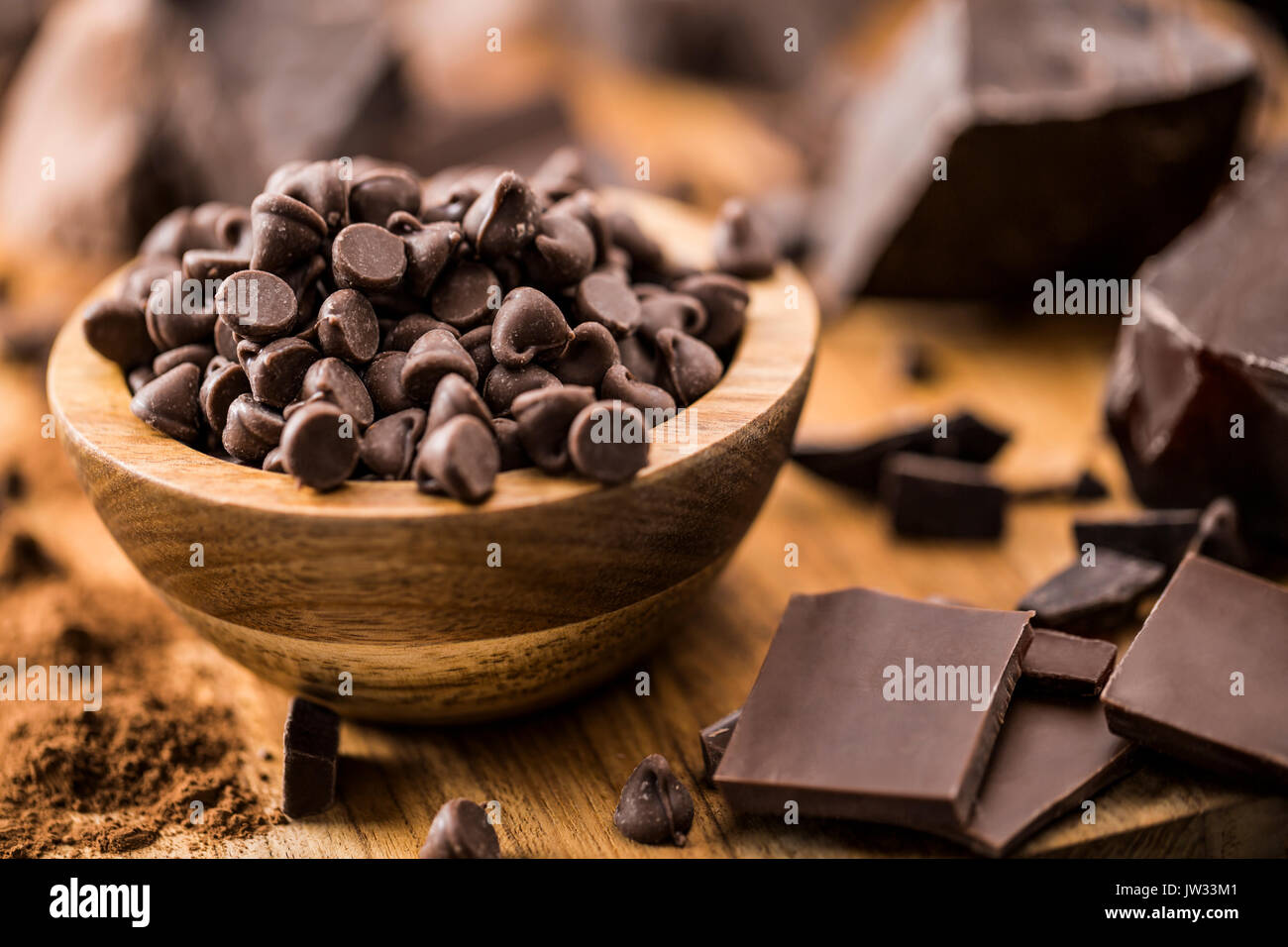 Tazza di gocce di cioccolato e vari pezzi di cioccolato sul tagliere Foto Stock