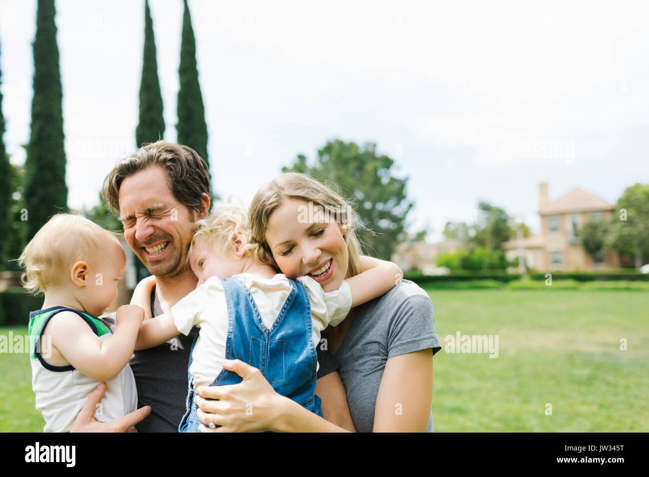 I genitori con figli (12-17 mesi, 4-5) abbracciando in posizione di parcheggio Foto Stock