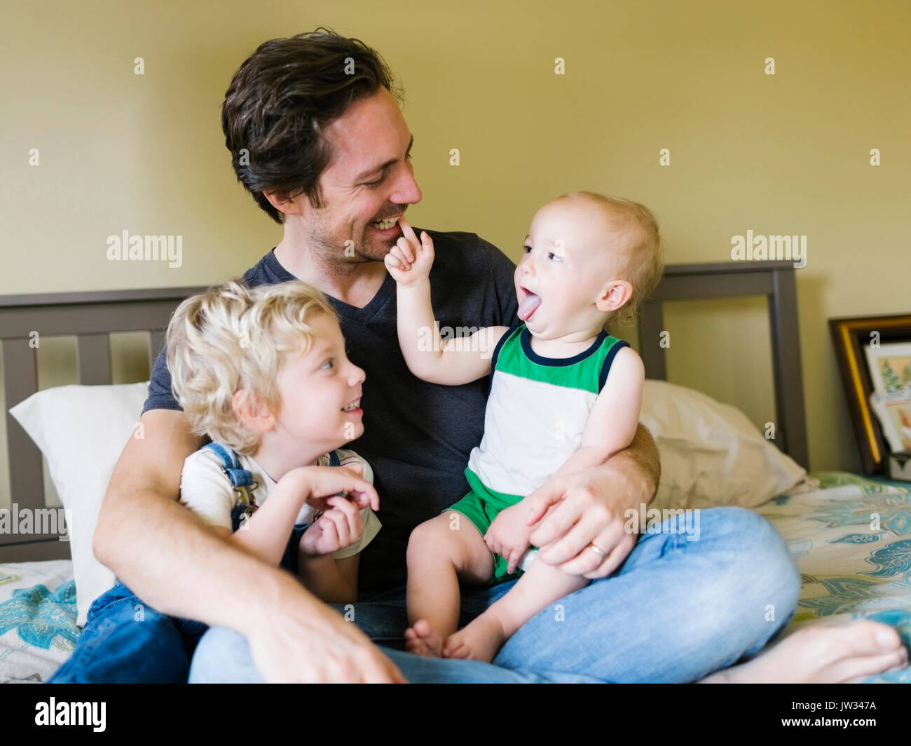 Padre giocare con figli (12-17 mesi, 4-5) in camera da letto Foto Stock