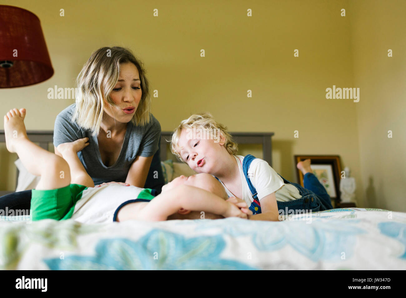 Madre giocando con figli (12-17 mesi, 4-5) in camera da letto Foto Stock