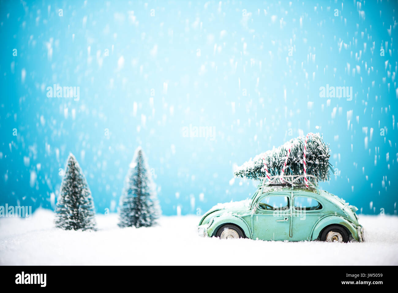 Auto d'epoca con pini albero di Natale sul tetto in nevicata correndo per il Natale attraverso la foresta in miniatura Foto Stock