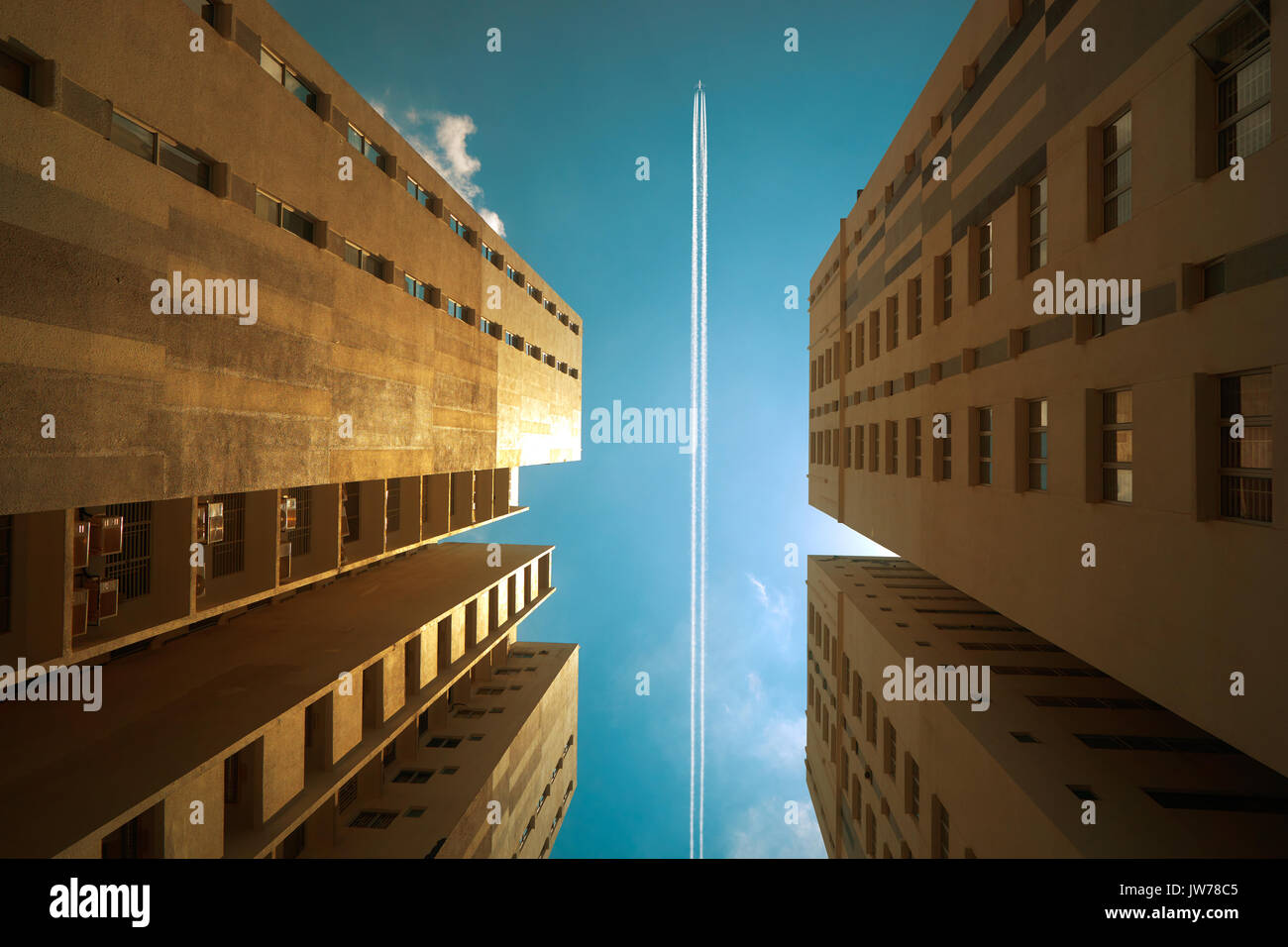 Aeroplano contrail contro il cielo blu chiaro con abstract basso angolo vista del comune di affari moderni grattacieli. Foto Stock