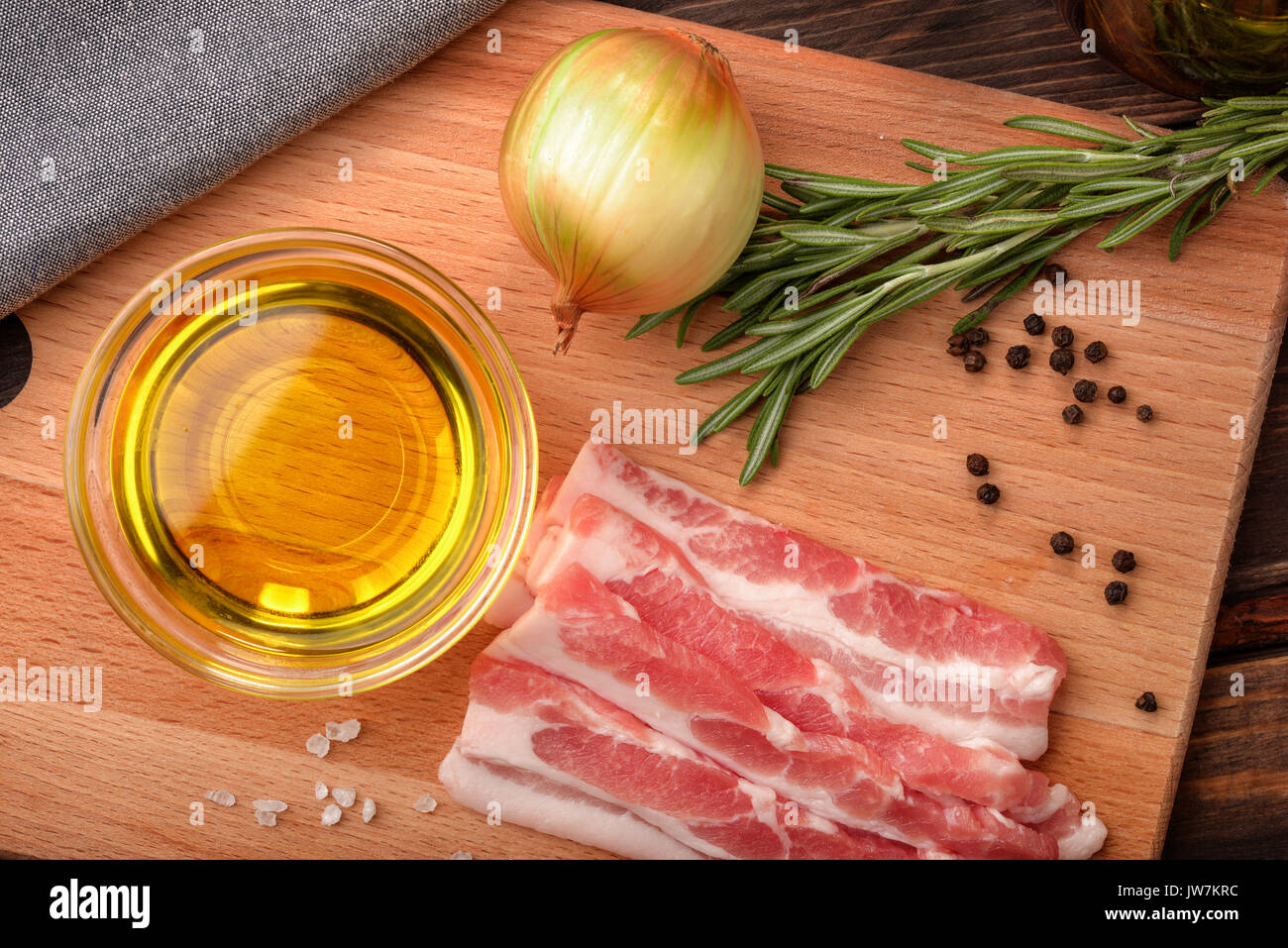Vista superiore di materie di pancetta, olio d'oliva, erbe e spezie su legno tagliere Foto Stock