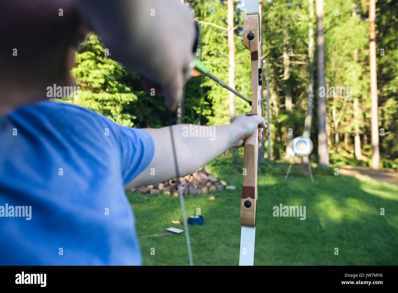 Sezione mediana del maschio maturo atleta di puntamento a freccia sulla scheda target nella foresta Foto Stock