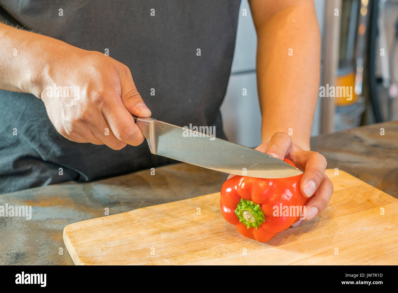 Lo Chef il taglio di peperone rosso su larga in legno Foto Stock