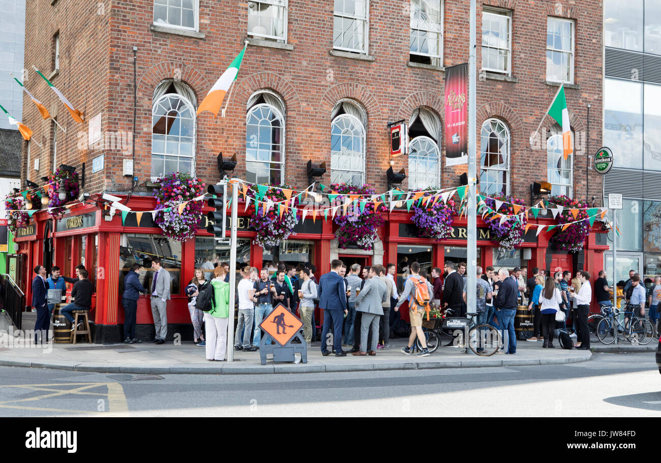 Gli uomini al lavoro a Dublino, Irlanda. Decine di persone bere al di fuori di un pub con degli uomini al lavoro sign in Irlanda la capitale Dublino. Foto Stock