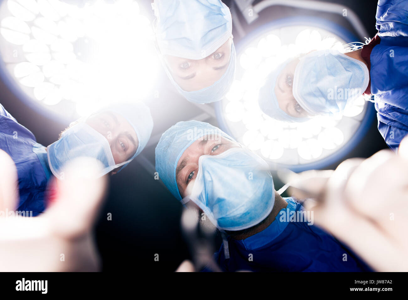 Il team di chirurghi operano sotto le luci di chirurgia nel funzionamento del teatro. Punto di vista colpo di dentisti di eseguire un intervento di chirurgia dentale in ospedale. Foto Stock