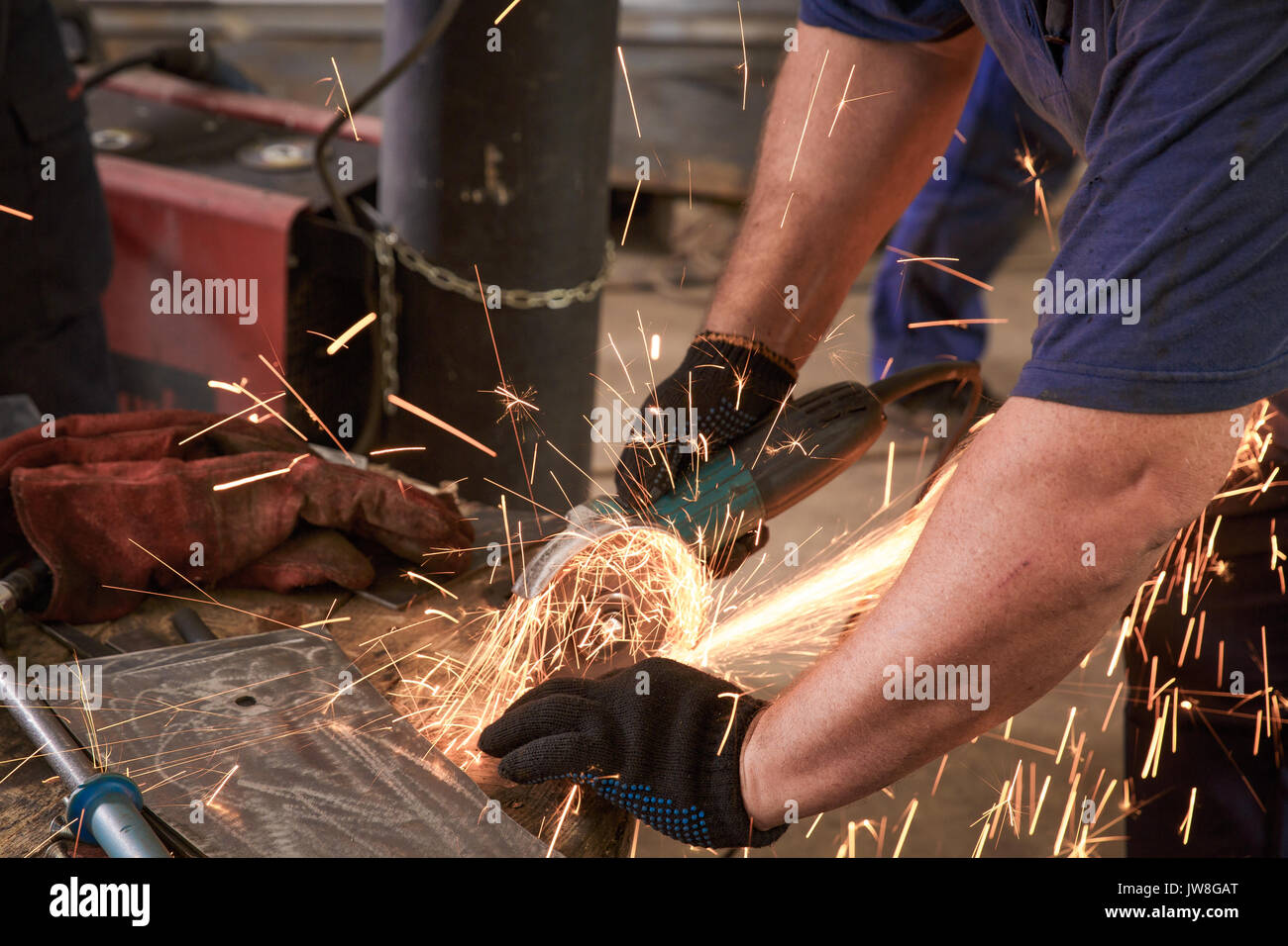 Close-up del lavoratore il taglio di metallo con la fresa. La formazione di scintille durante la rettifica di ferro. Foto Stock