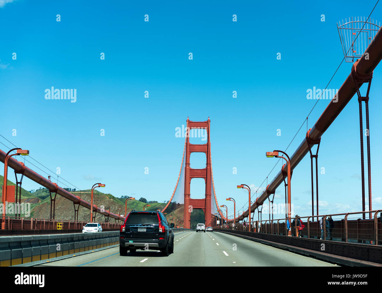Auto che attraversa il Golden Gate Bridge, San Francisco - struttura in acciaio rosso contro il cielo blu luminoso Foto Stock