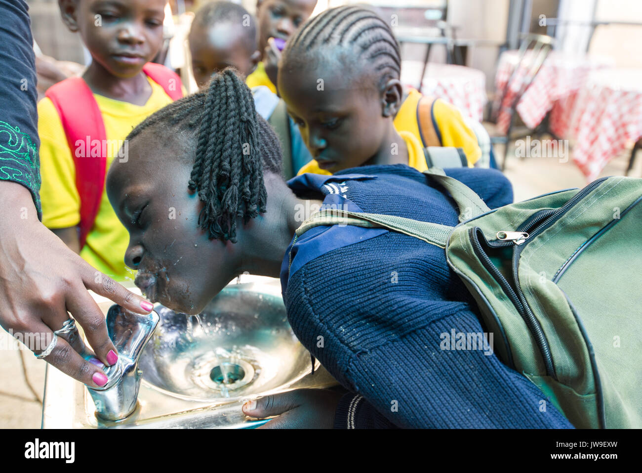 I giovani della scuola i bambini da Kibera bere dalla fontana di Kibera Town Center, Nairobi, Kenia Foto Stock