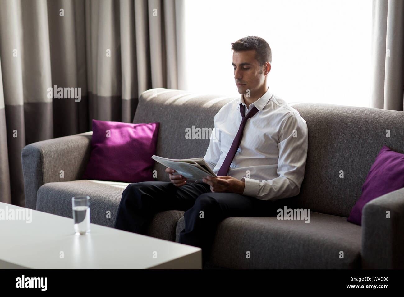 Imprenditore leggendo il giornale in camera di albergo Foto Stock