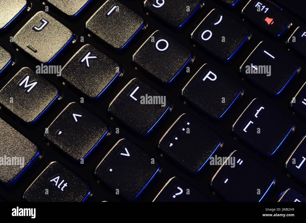 Angolo di visualizzazione della chiusura del laptop nero tastierino con lettere in bianco, figure e simboli. La luce proveniente dal lato sinistro superiore. Foto Stock
