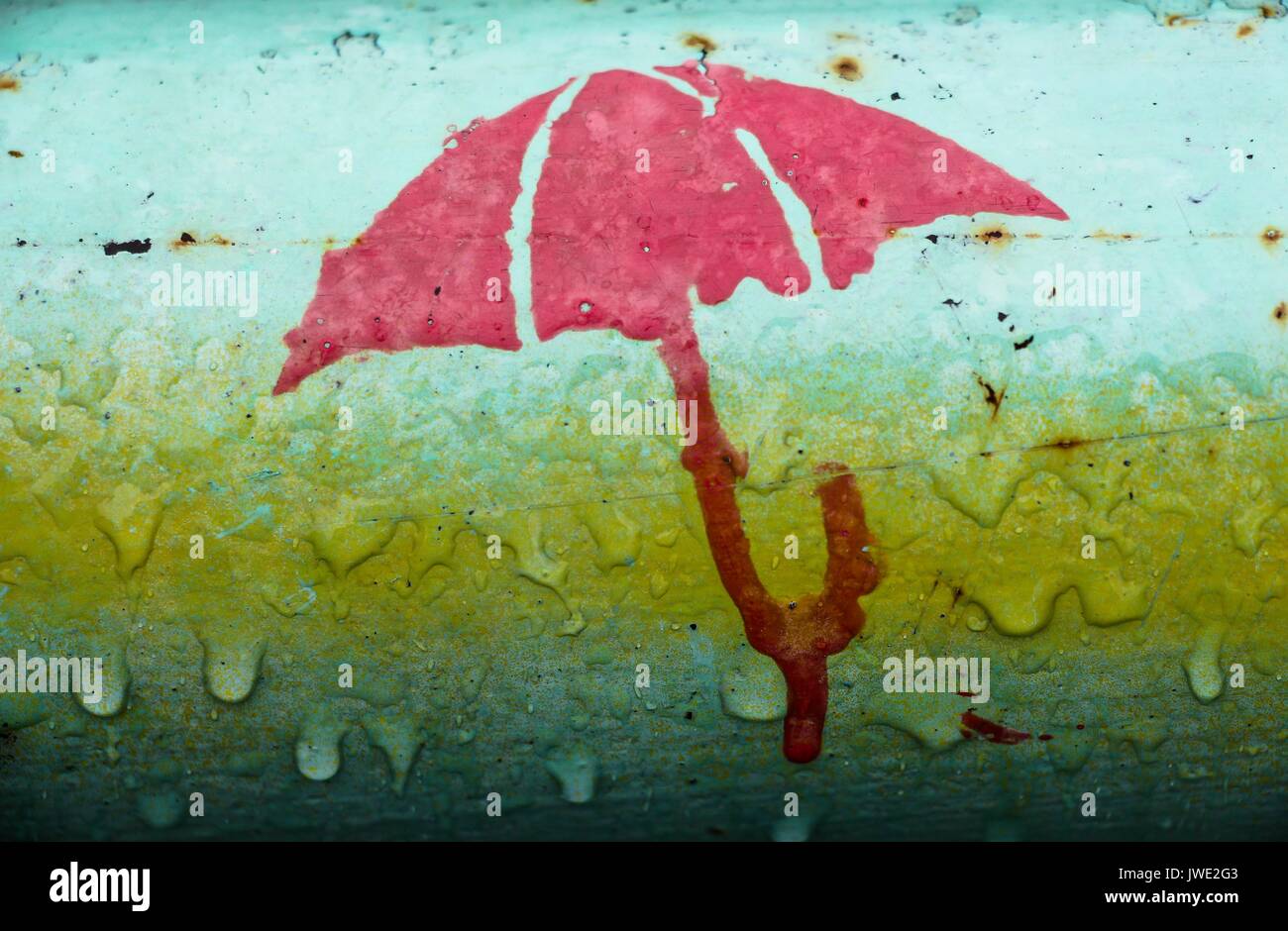 La figura di un ombrello su un tubo di ferro. La foto è stata scattata  durante la pioggia e sembra che l'ombrello fonde sotto l'influenza  dell'acqua. Gocce di ar Foto stock -