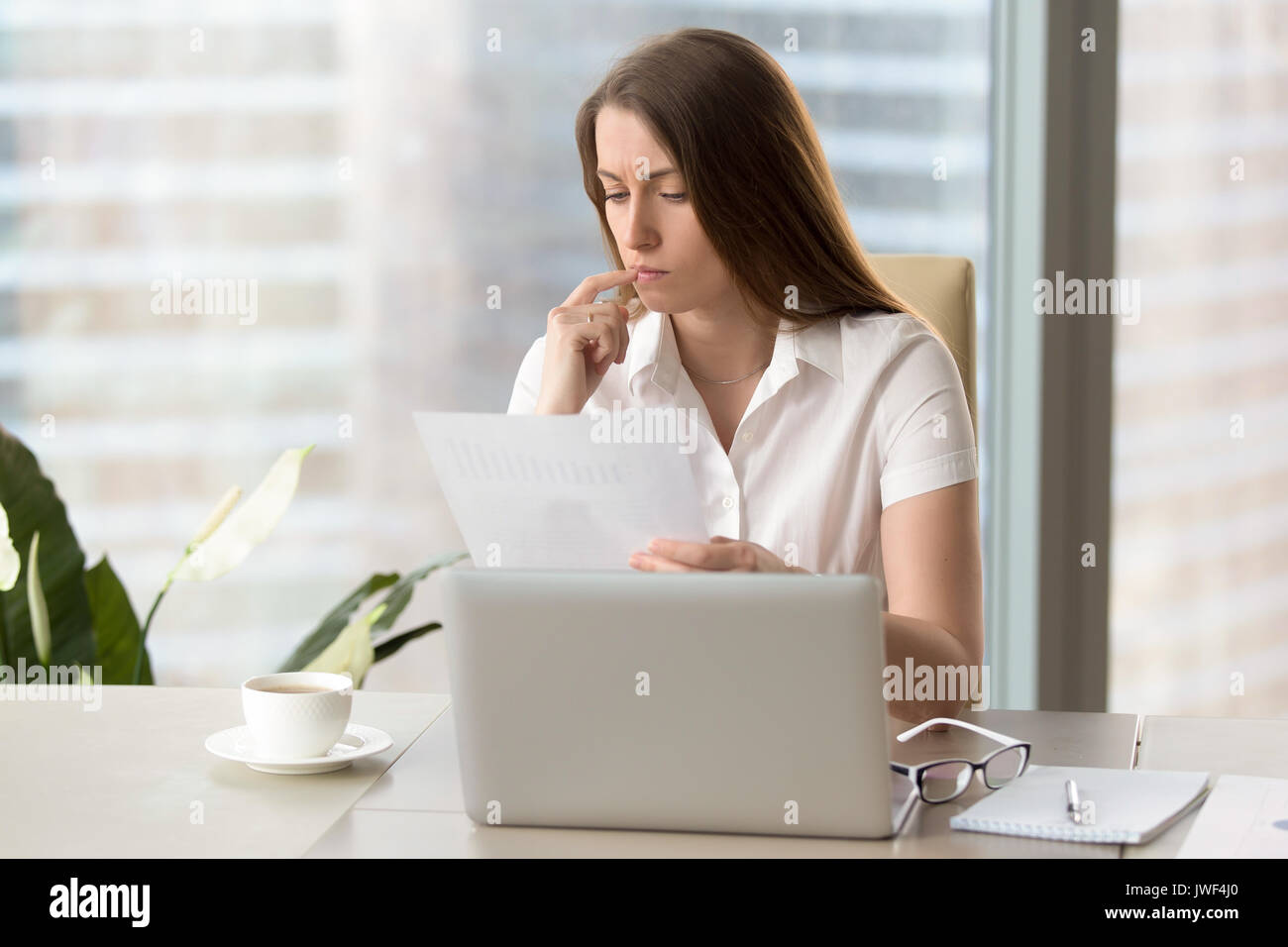 Concentrati concentrati imprenditrice analizzando il documento, tenendo f Foto Stock