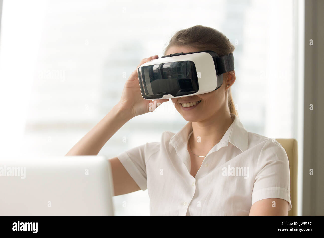 Donna sorridente cercando gli occhiali VR, primo casco di realtà virtuale e ciò ex Foto Stock