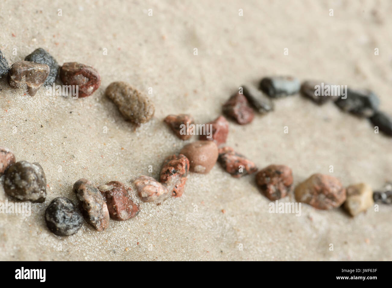 Pebble simbolo di infinito su sfondo sabbia messa a fuoco selettiva Foto Stock