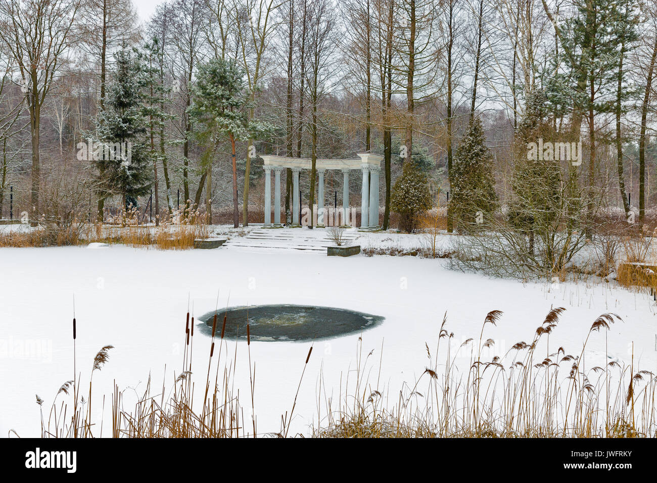 Padiglione con colonne e inverno lago con foro di ghiaccio nel parco Foto Stock