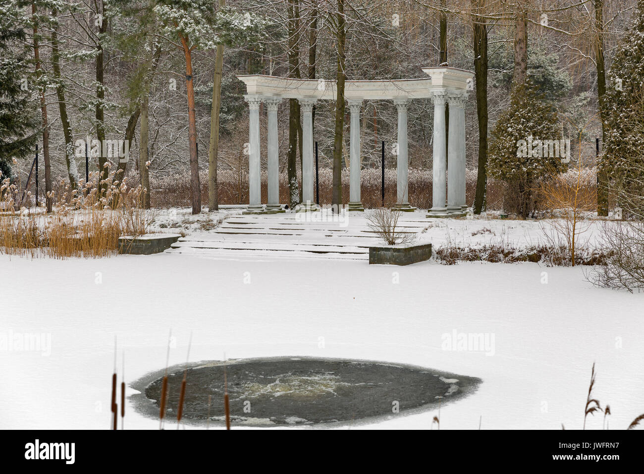 Padiglione con colonne e inverno lago con foro di ghiaccio nel parco Foto Stock