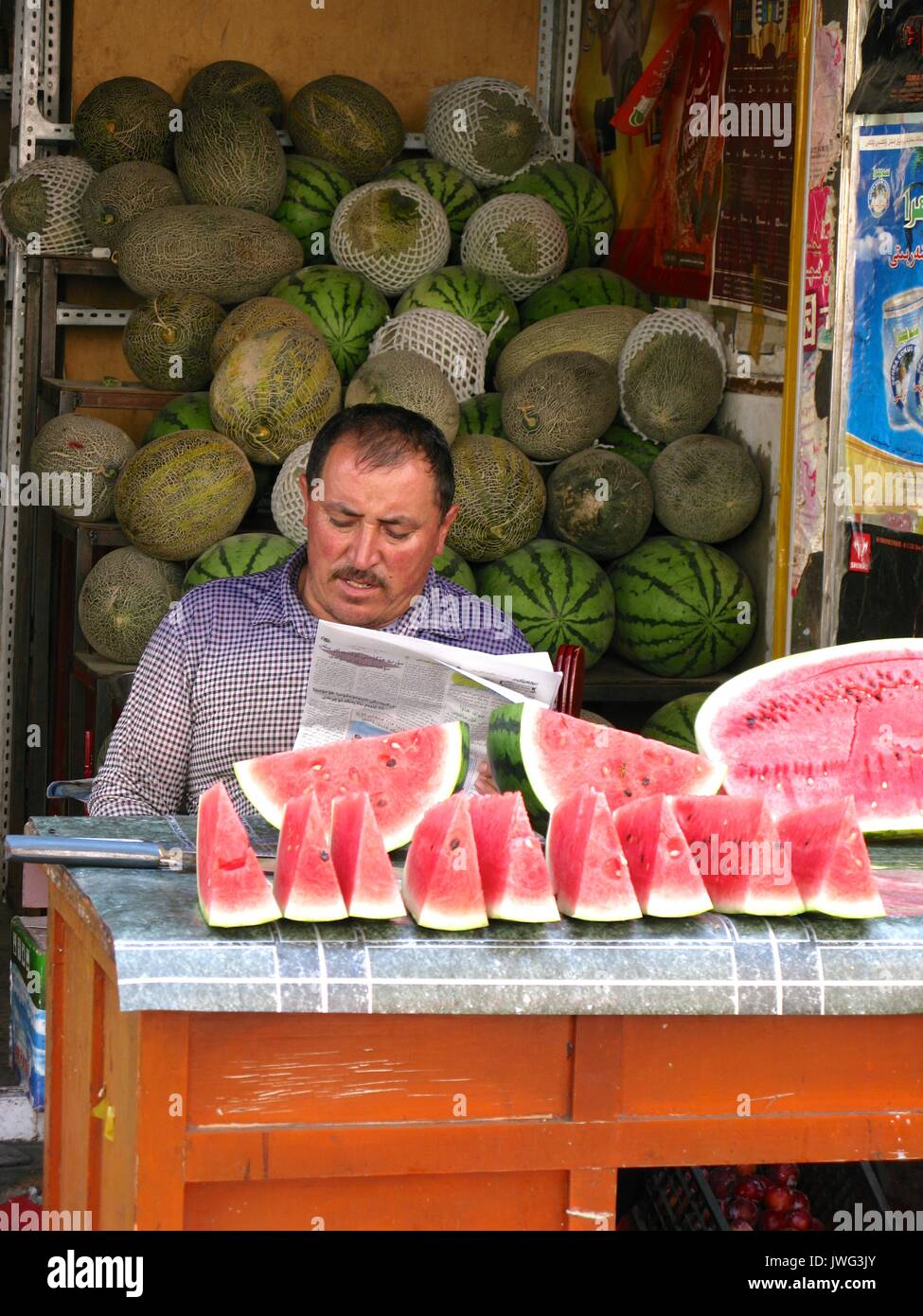Anguria venditore leggendo il giornale in Urumqi mercato vecchio Foto Stock