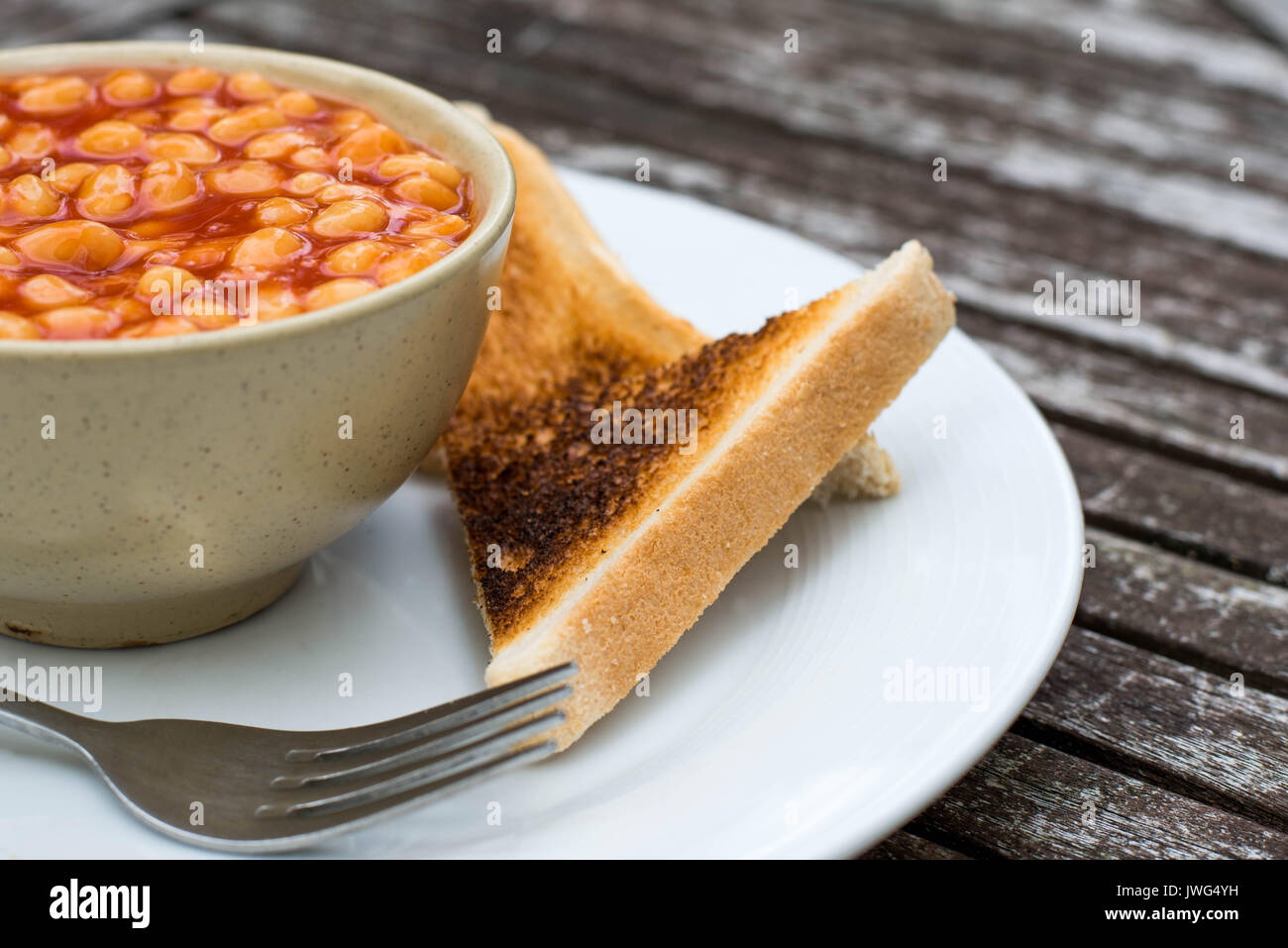 Fagioli in salsa di pomodoro secco con toast contro un rustico sfondo di legno Foto Stock