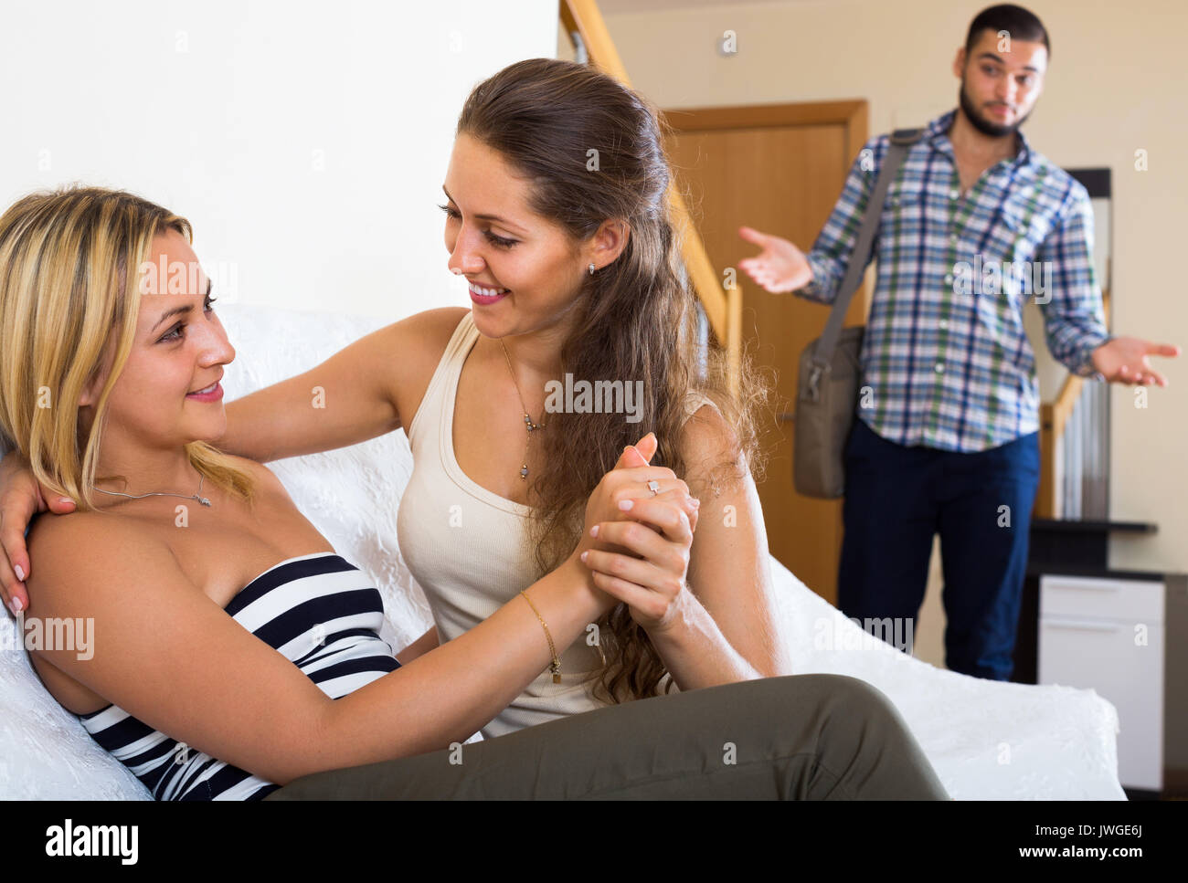 Spiacevolmente sorpreso giovane uomo alla scoperta della sua fidanzata con un'altra donna a casa Foto Stock