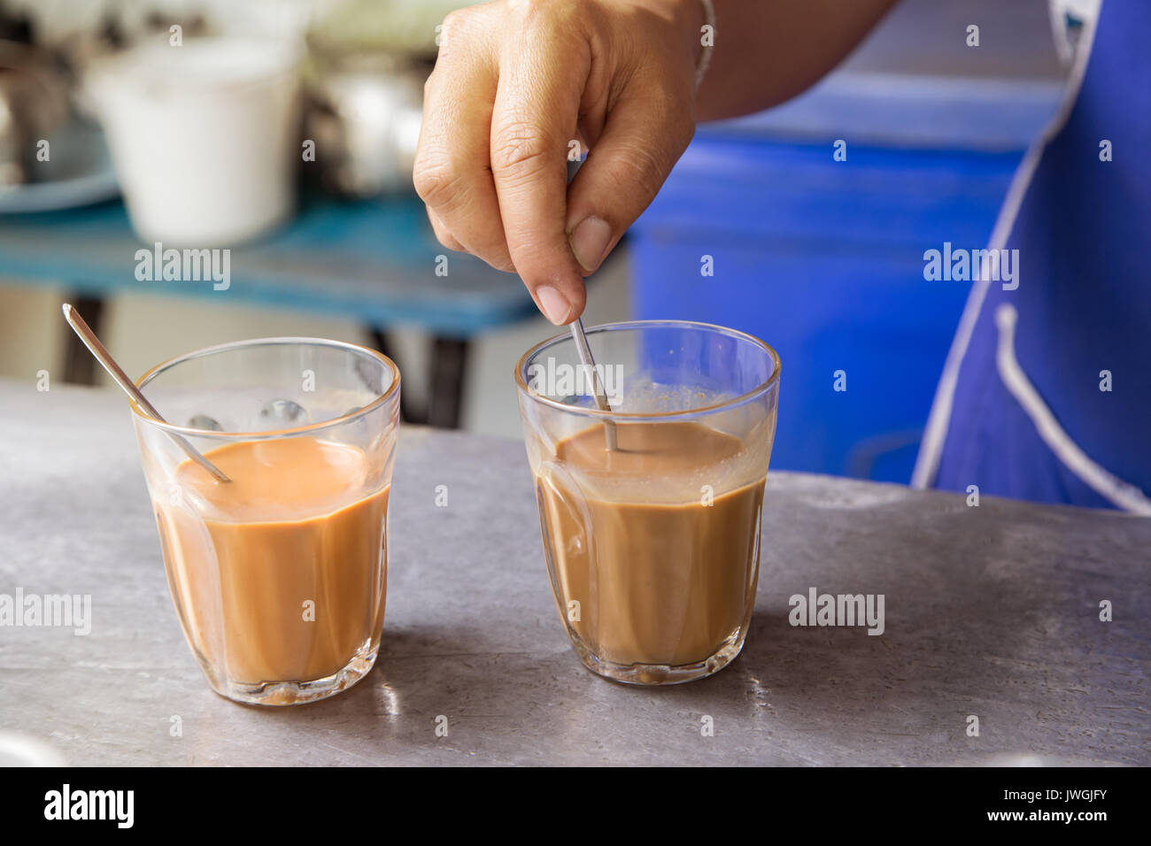 Hot Thai tè latte tenere in mano il cucchiaio infusore firma mista bevanda locale Foto Stock