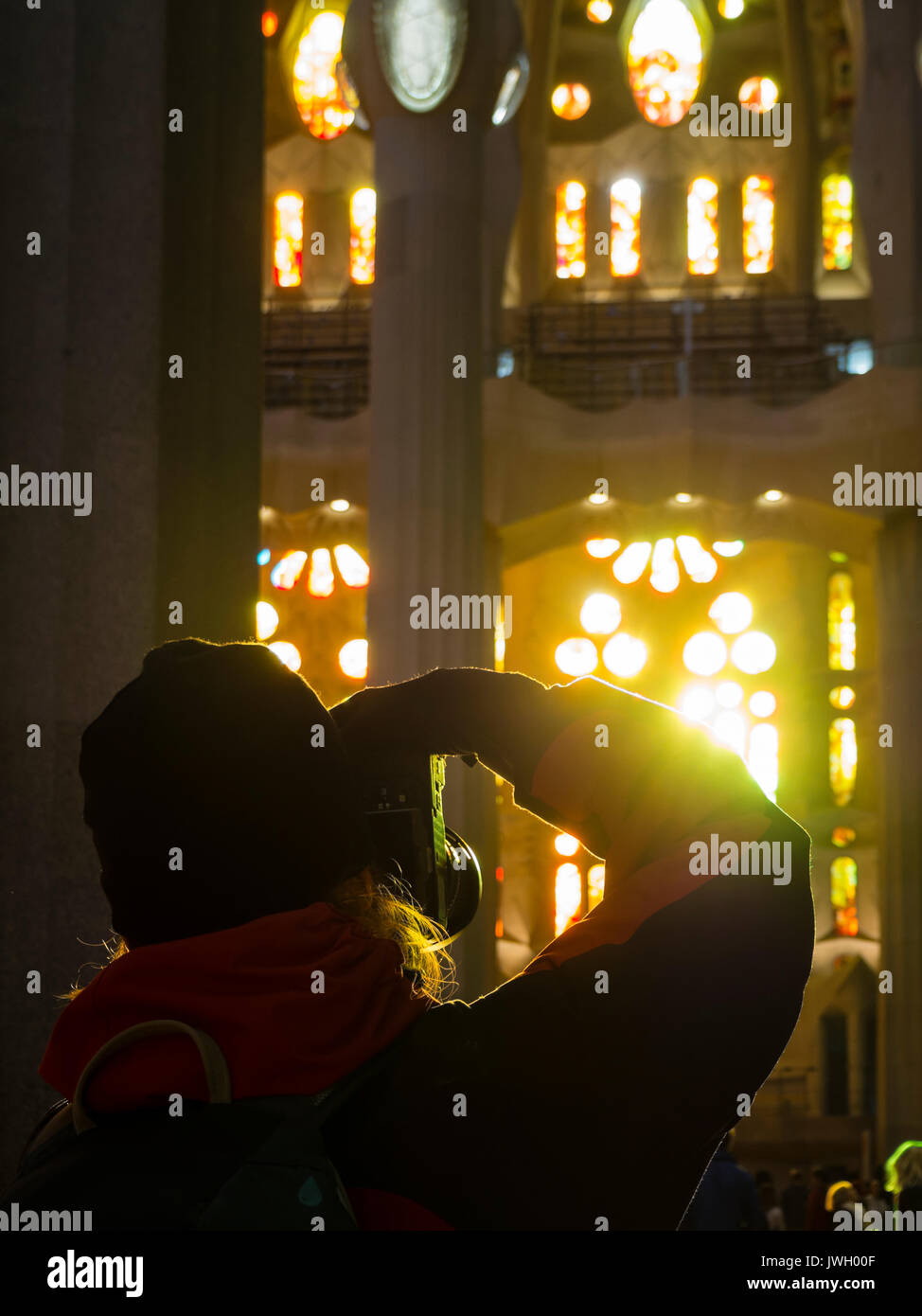 Un turista è di scattare foto delle finestre verniciate della facciata occidentale dentro la Sagrada Familia di Barcellona cattedrale. L'ancora incompiuta dal punto di riferimento Foto Stock