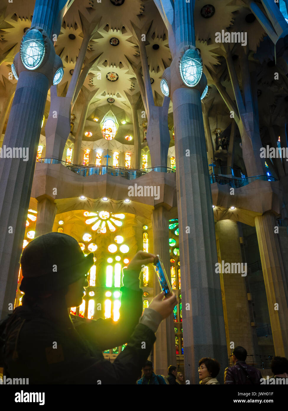 Un turista asiatico è di scattare foto con uno smartphone all'interno la Sagrada Familia di Barcellona cattedrale che è affollata di turisti da tutto il wor Foto Stock