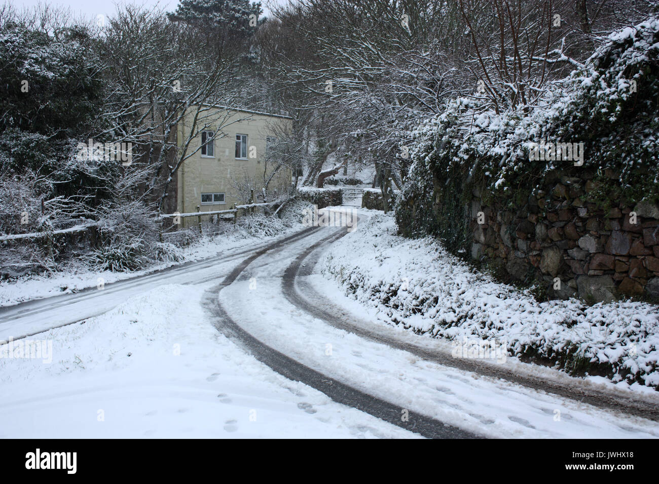 British Isole del Canale. Alderney. Scena invernale di cottage e coperti di neve vicolo del paese. Foto Stock