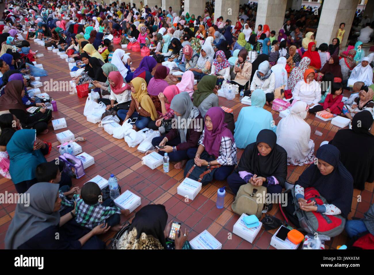 Migliaia di persone indonesiano rompere il loro rapido presso la Moschea Istiqlal a Jakarta, Indonesia. Ogni giorno durante il mese sacro del Ramadan, la scheda della moschea rende 3 mila razioni di cibo distribuito gratuitamente ai poveri e pellegrini. In Ramadan i musulmani non mangiare, bere o fumare dall alba al tramonto. Foto Stock