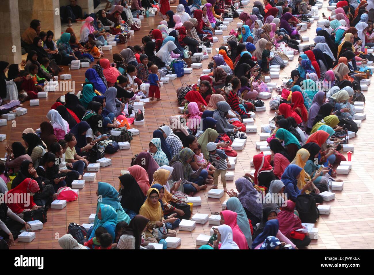 Migliaia di persone indonesiano rompere il loro rapido presso la Moschea Istiqlal a Jakarta, Indonesia. Ogni giorno durante il mese sacro del Ramadan, la scheda della moschea rende 3 mila razioni di cibo distribuito gratuitamente ai poveri e pellegrini. In Ramadan i musulmani non mangiare, bere o fumare dall alba al tramonto. Foto Stock