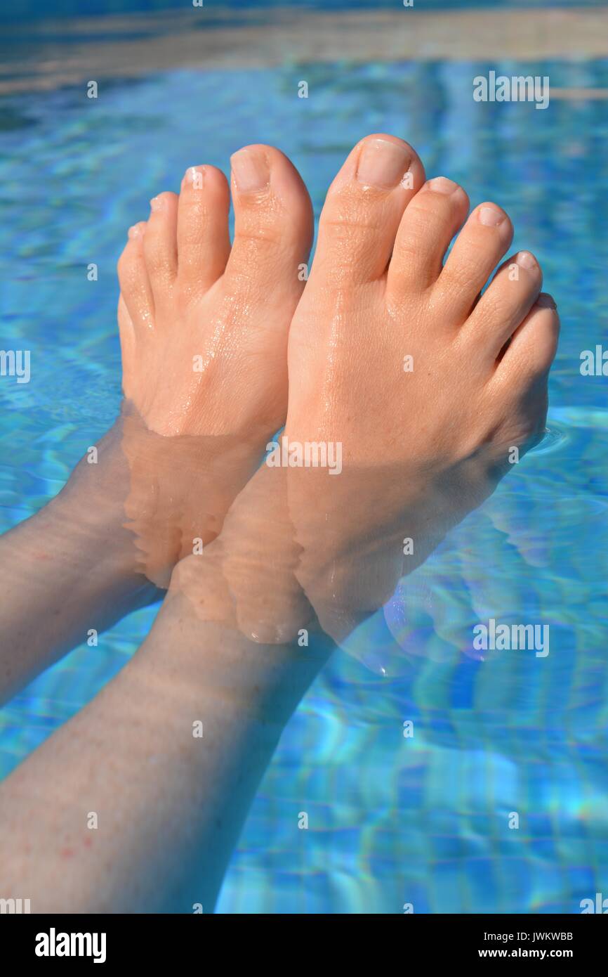 Donna flottante in una piscina, close up dei piedi Foto Stock