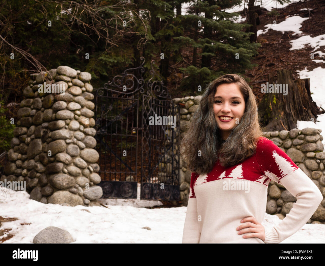 Una sorridente ragazza teen in bianco e rosso maglione da un cancello di ferro con pilastri di pietra in inverno Foto Stock Una sorridente ragazza teen in bianco e rosso maglione da un cancello di ferro con pilastri di pietra in inverno Foto Stock