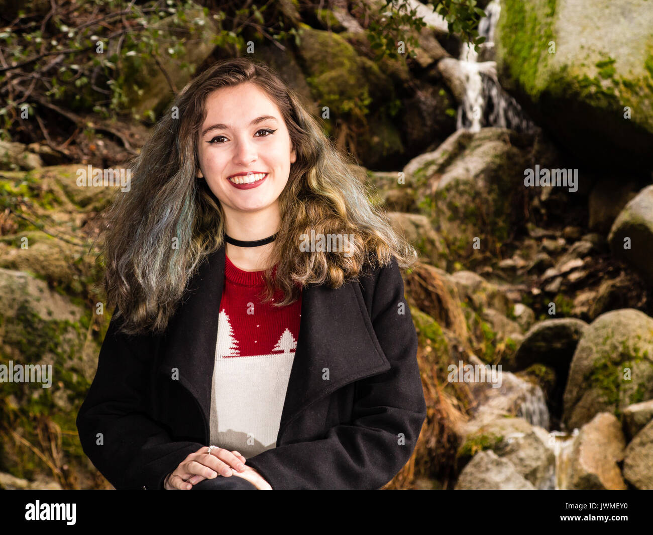 Ritratto di un grazioso sorridente ragazza adolescente in maglione e mantello nero in natura Foto Stock