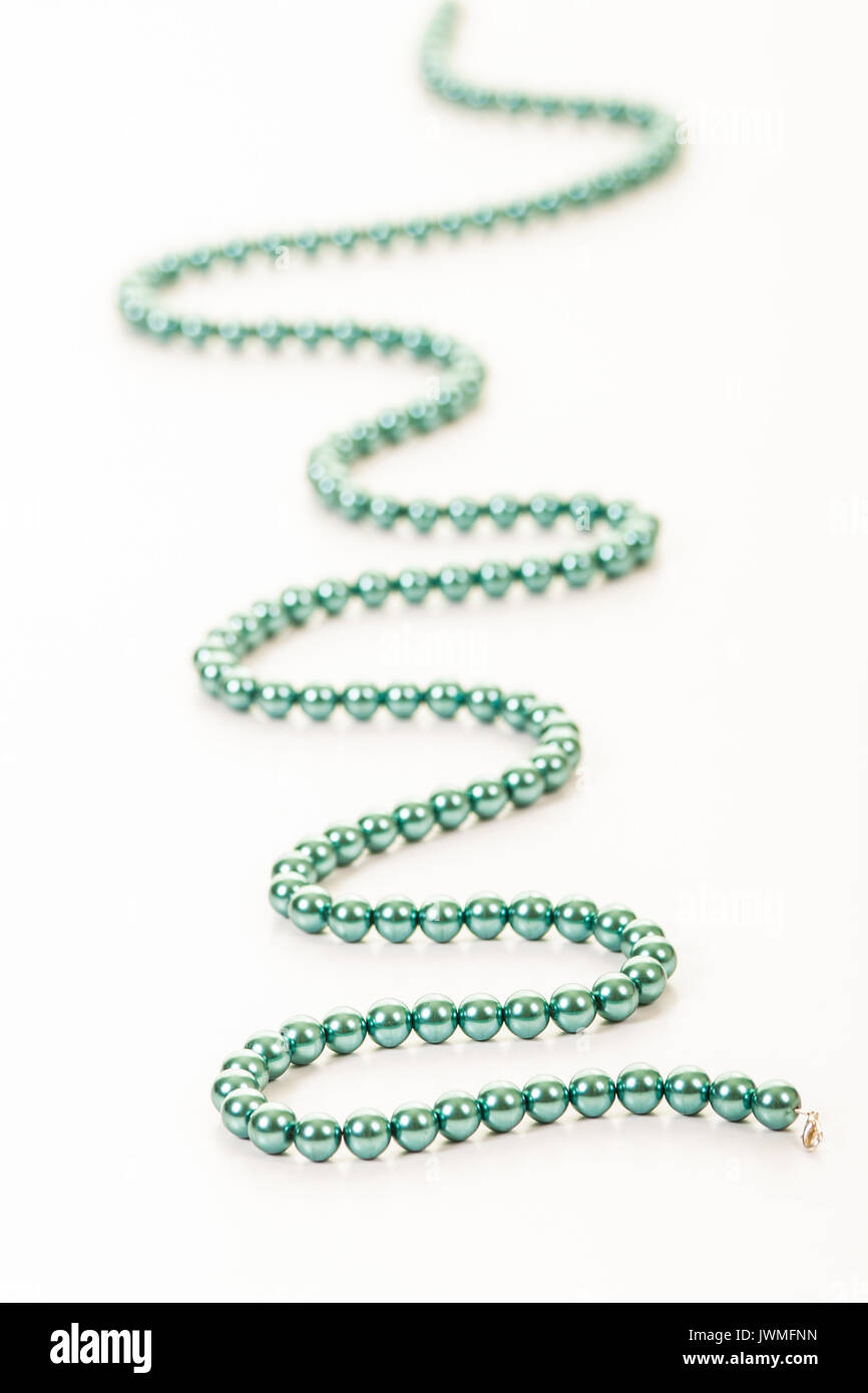 Una stringa di bella turchese perline colorate su di una superficie bianca Foto Stock