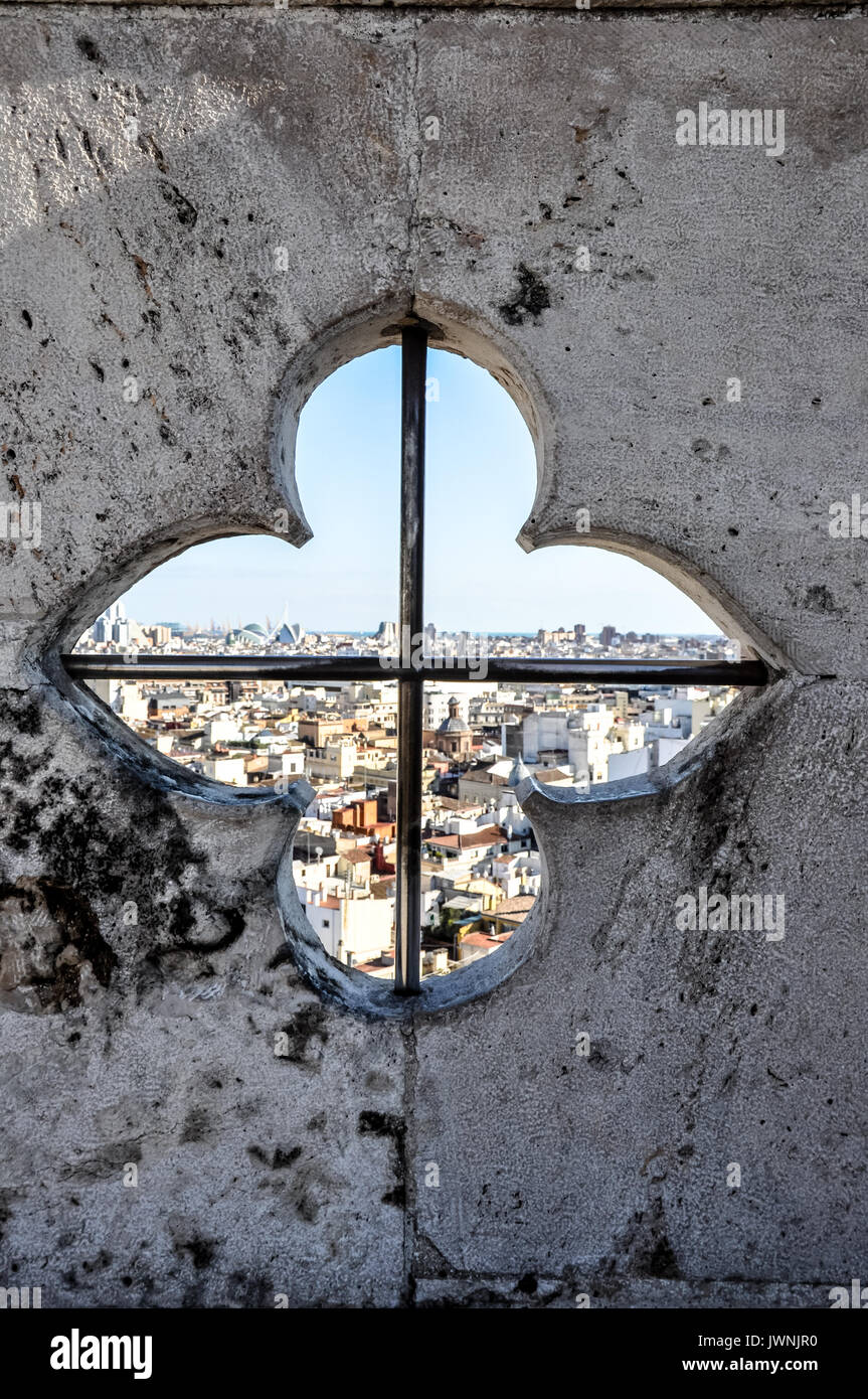Vista di una città attraverso una apertura simmetrica quadrifoil cattedrale window set nel calcestruzzo in Valencia, Spagna Foto Stock