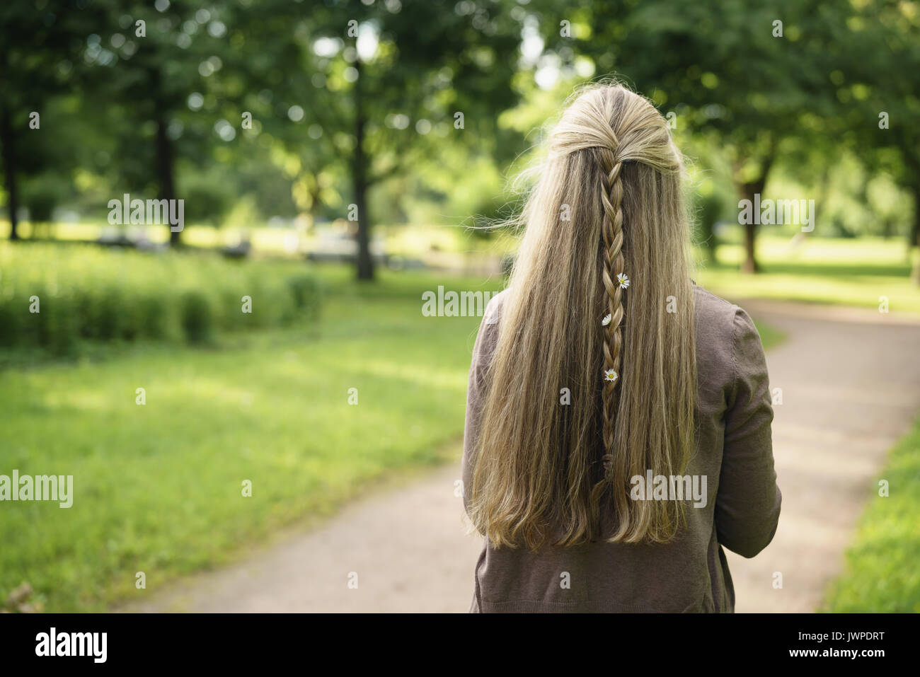 Teen ragazza con daisy fiori nei capelli in parco verde da dietro nel giorno di estate, lifestyle ritratto Foto Stock